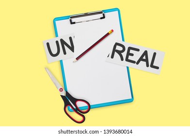 Single metal sharp scissors with black and red plastic handles near clipboard, pencil, cut paper with handwritten inscription unreal on yellow table. Top view. Copy space for your text