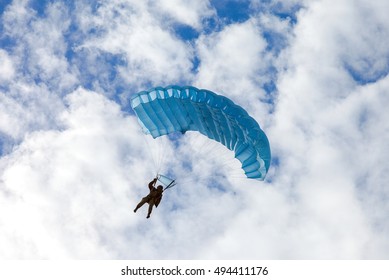 Single Military Parachute Jumper On A Blue Wing Parachute On Blue Sky Background