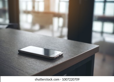 A Single Mobile Phone On Wooden Table In The Office