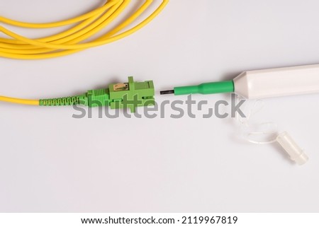 Single mode patch cord with SC-APS connector and adapter, fiber optic cleaner next to the patch cord