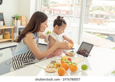 Single Mom And Daughter Open A Tablet, Learn Online, How To Cook, Prepare Breakfast, Go Together In The Kitchen. 