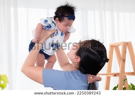 Single mom and newborn baby play together at home, mother holding adorable infant in air and looking with love and tender. Spend time together with trust. Senior women making funny faces to toddler.
