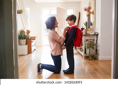Single Mother At Home Getting Son Wearing Uniform Ready For First Day Of School