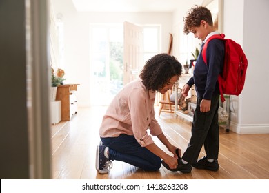 Single Mother At Home Getting Son Wearing Uniform Ready For First Day Of School