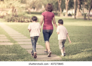 Single Mother Walking In The Park With Sons