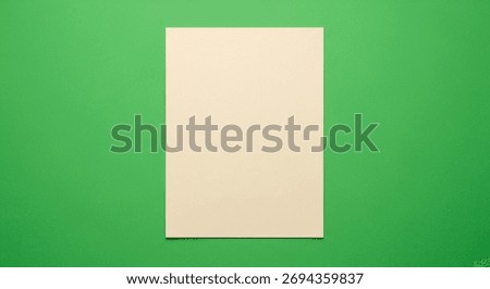 A single off-white rectangular paper sheet placed vertically on a solid green background, creating a simple and clean minimalistic composition.