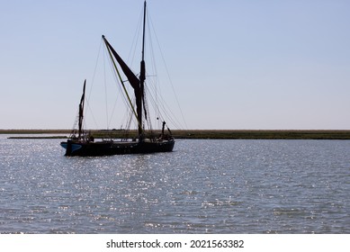 Single old traditional Sailing barge on river in England, sails tied up