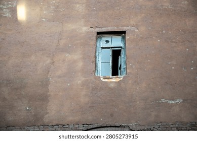 A single old window on an empty wall of a historical building.