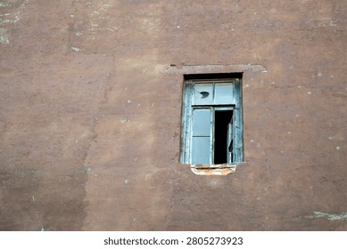 A single old window on an empty wall of a historical building.
