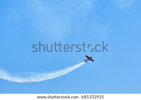 Single one sport plane of aerobatic team vapour trails in blue sky. Plane white vapour trails tracks background. Plane aerobatic maneuver stunt. Stunt planes aerobatic team vapor trails MAKS-2017