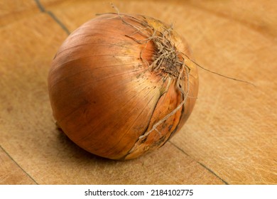 A Single Onion Sits On A Worn Butcher Block Cutting Board