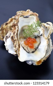 single opened oyster with a salmon roe and dill garnish