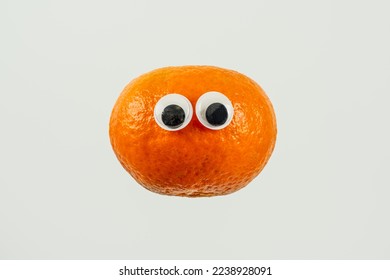 single orange satsuma tangerine with googly cartoon eyes isolated on a white background