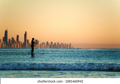 Single Paddler Against The Gold Coast Skyline At Sunset.