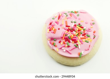 A Single Pink Frosted Sugar Cookie With Colorful Sprinkles Isolated On A White Background