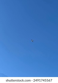 Single plane flying high above on a day with no clouds, blue sky