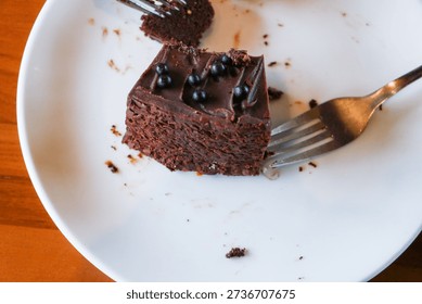 A single portion of dense chocolate cake accompanied by metal forks