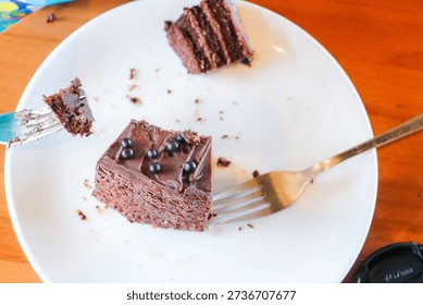 A single portion of dense chocolate cake accompanied by metal forks