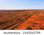 Single railway line to Broken Hill mining city through red soil australian outback with Broken Hill- Sydney passenger train - aerial landscape.