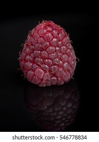 Single raspberry on black background