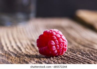 Single raspberry on a wooden table