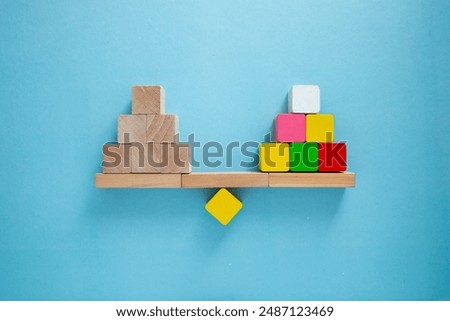 Single red block is outweighing a stack of wooden cubes on a seesaw, symbolizing the power of individuality