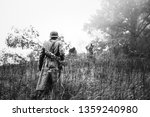 Single Re-enactor Dressed As German Wehrmacht Infantry Soldier In World War II Walking In Patrol Through Autumn Forest. WWII WW2 Times. Photo In Black And White Colors.