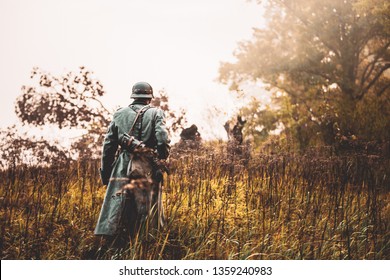Single Re-enactor Dressed As German Wehrmacht Infantry Soldier In World War II Walking In Patrol Through Autumn Forest. WWII WW2 Times.