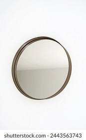 Single round or circular mirror with a brass or bronze coloured surround hanging a a plain white wall. Modern, elegant and stylish. Close up minimalist interior design detail