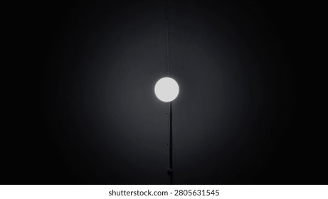 A single round light bulb glowing brightly in the center of a dark room background.