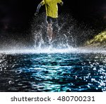 Single runner running, making splash in a stream during night.