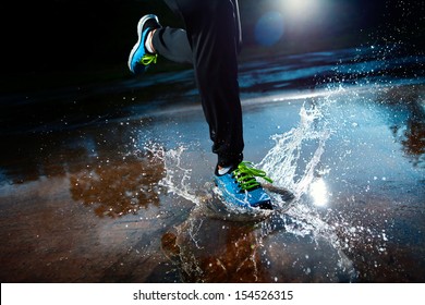 Single Runner Running In Rain And Making Splash In Puddle