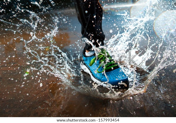 Single\
runner running in rain and making splash in\
puddle