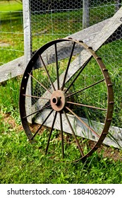 Single Rusty Old Wagon Wheel Leaning on Fence