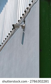Single security CCTV camera on industrial building wall from below.