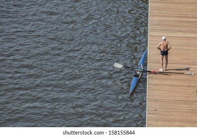 single senior standing backside by row boat on deck by river with hat - Powered by Shutterstock