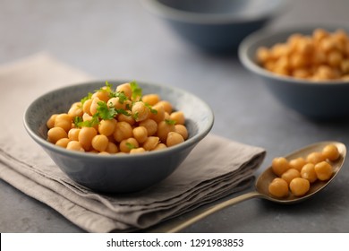 Single serving of chickpeas in pretty grey bowl on linen napkin garnished with parsley