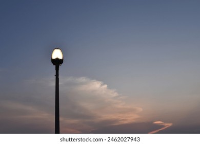 single silhouette street lamp with dramatic dusk sky, street light turned on against twilight atmosphere with copy space - Powered by Shutterstock