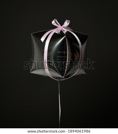 Single silver present gift box balloon ballon object with pink stripe for birthday or valentines day on dark gray background
