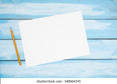 Single Simple Empty White Paper Notebook With A Blank For Drawing Or Writing Is On A Desktop Blue Plank Wood. Top View. Mockup. Flat Lay