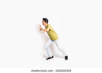 The single skinny young male tries to push something sideways. The full body of an Asian or Indonesian person. Isolated photo studio with white background. - Shutterstock ID 2242265103