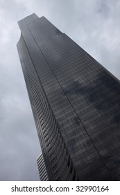 a single skyscraper against a clouded sky