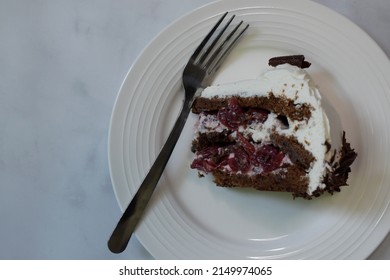 A single slice of black forest cake with vanilla whipped cream and chocolate shavings for decoration. 