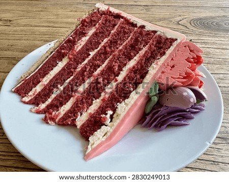 Single Slice of Five-Layer Red Velvet Cake with Pink Frosting on White Plate on Rustic Wood Table