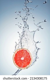 A single slice of fresh red grapefruit being splashed with water. Beautiful water splash on a juicy piece of citrus grapefruit. Fresh natural orange citrus flavour.
