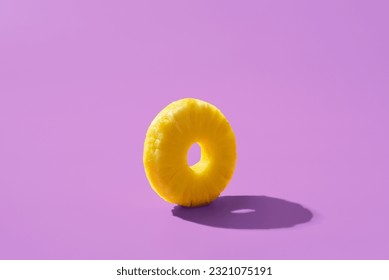 Single slice of pineapple isolated on a purple background. Pineapple ring in bright light minimalist on a colorful table.