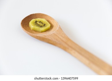 Single Slice Yellow Kiwi Fruit On Wooden Spoon With White Background