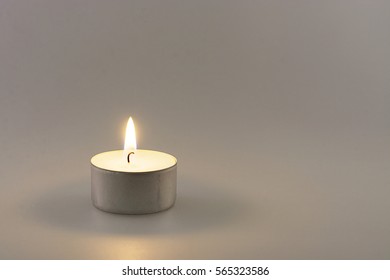Single small burning candle light bringing comfort, light and warmth