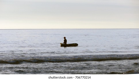 Single small raft with one person out in the ocean   drifting gazing calming hat                    