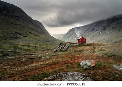 A single small red cabin billows smoke from it's tiny chimney in the remote gorge of central Norway. The distant dark clouds give the feeling of isolation and remoteness. Shot during autumn  - Powered by Shutterstock